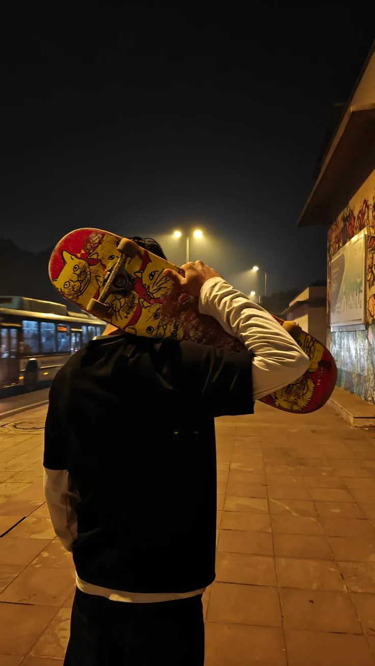 Skateur de nuit, planche graphique sur l'épaule.